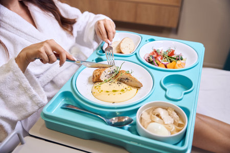 Cropped pregnant woman cutting meat with knife and fork during having lunchの写真素材