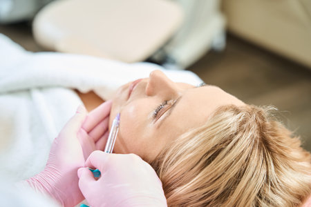 Partial female beautician doing face beauty injection of woman in beauty salonの写真素材