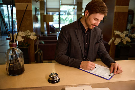Cropped photo of young businessman filling registration form at hotelの写真素材