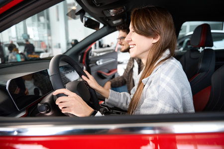 Couple sitting in new car visiting auto dealership for choosing automobile