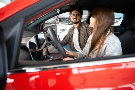 Man and enjoying while choosing and buying new car at showroom testing vehicle