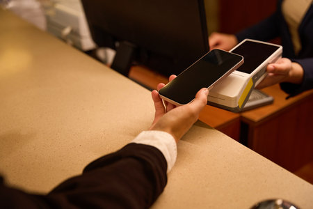 Cropped photo of hand paying with phone over terminal
