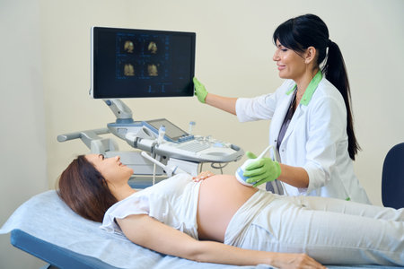 Gynecologist looking at pregnant woman looking at monitor during ultrasound
