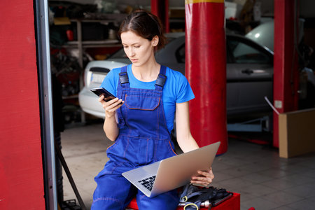 Female auto mechanic with a laptop in car repair shopの写真素材