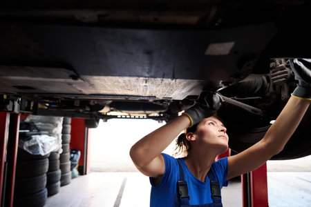 Young woman inspecting the underbody of a carの写真素材