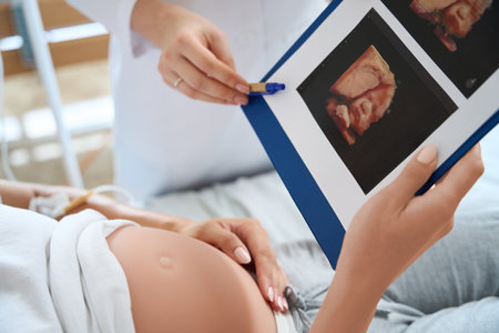 Cropped of doctor showing ultrasound photo to pregnant woman of her future baby