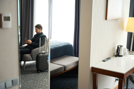 Man in traveling suit sits with mobile phone in chair