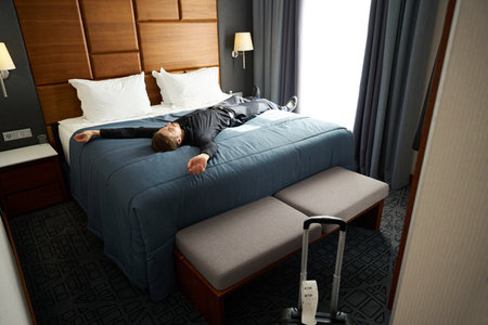 Man lies with his arms outstretched on a large bed