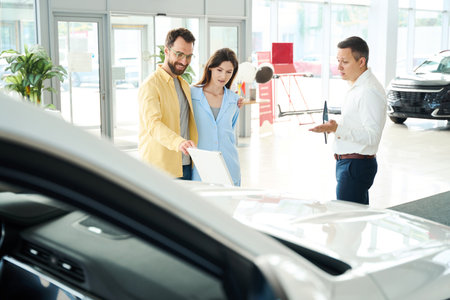 Couple in a car dealership communicates with a consultant