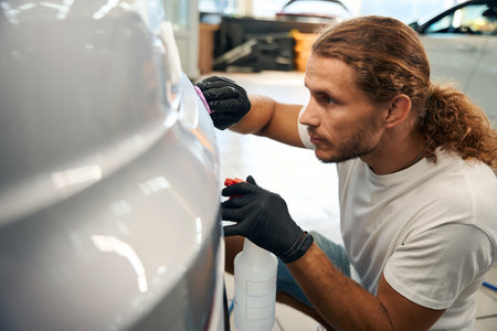Young man works with special clay in car detailing