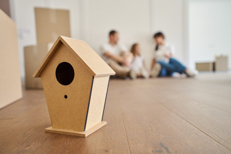 Focus on wooden birdhouse like new family nest with blurred family on background