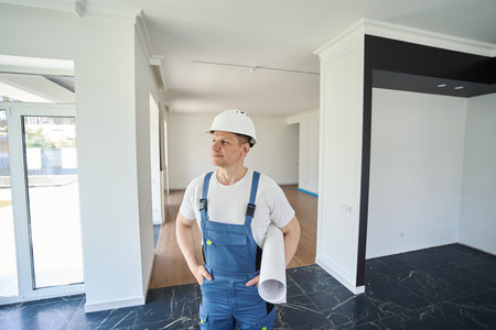 Male worker or architect with hands in pocket looking away in modern townhouse
