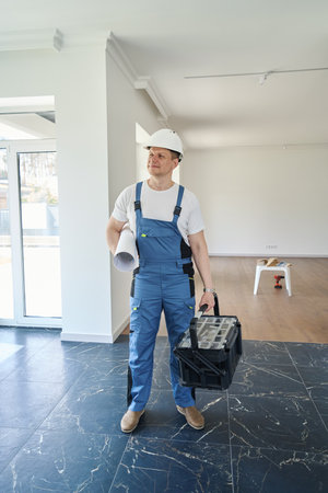 Male worker with blueprint and toolbox in new modern comfortable townhouseの写真素材