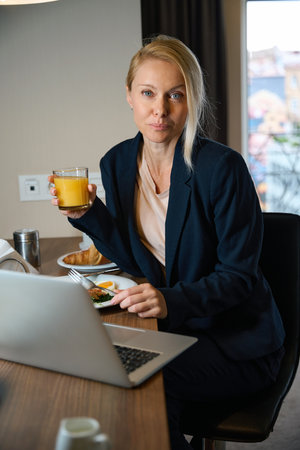 Female entrepreneur having lunch in front of laptop in roomの写真素材