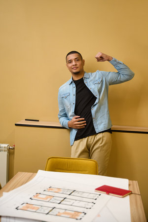Positive guy standing while bending his arm to show strength