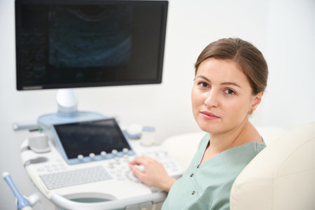 Female doctor looking at camera while working on ultrasound machine in clinicの写真素材