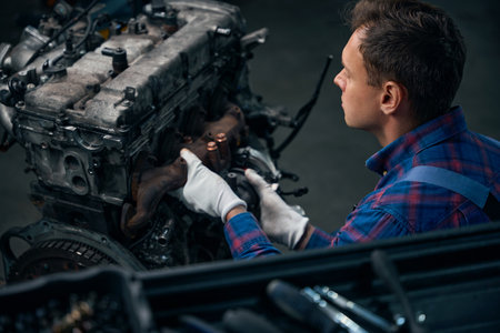 Male installing exhaust manifold on machine engine
