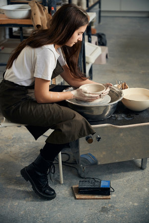 Female potter engaged in craft on potters wheel and making clay productの写真素材