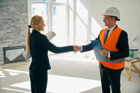 Woman and foreman standing in room and shaking hands