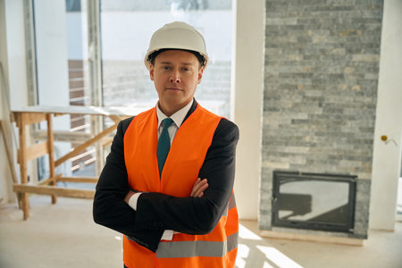 Construction engineer standing in room with folded arms across chest
