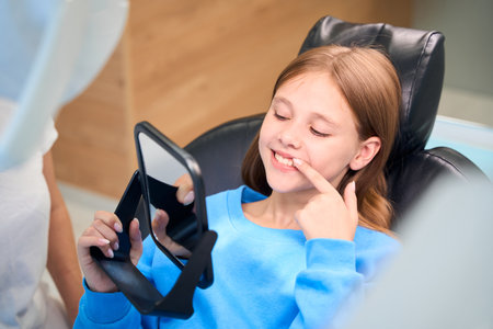 Child admires her white teeth in the mirror