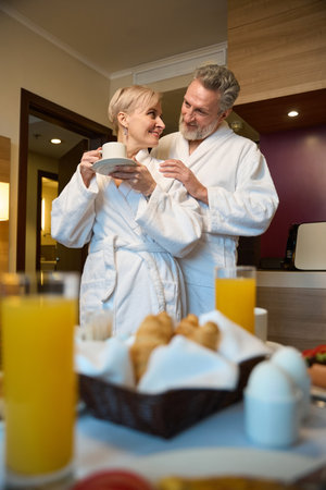 Bottom of man hugging happy wife drinking coffee and they looking at each otherの写真素材