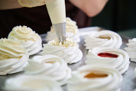 Confectioner squeezing whipped cheese cream from pastry bag at merengue nestの写真素材