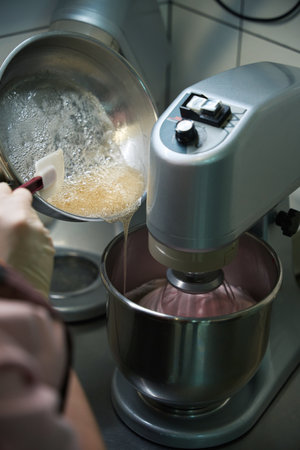 Confectioner pouring heated mixture of gelling agent and sugar into berry pureeの写真素材