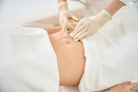Close-up medical worker making injection of hormones into woman client stomachの写真素材