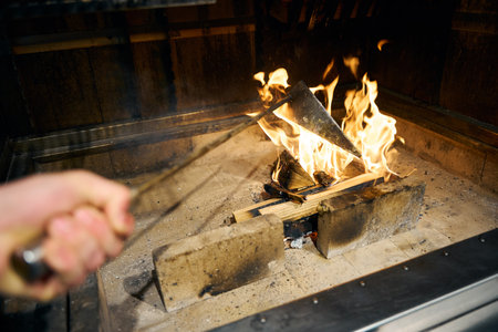 Male chef frying some food in iron triangle pot in burning fire placeの写真素材