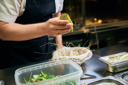 Partial male chef pouring oil or spice in oyster in nest plate in restaurantの写真素材
