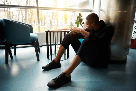 Sad guy sitting on floor and looking through window