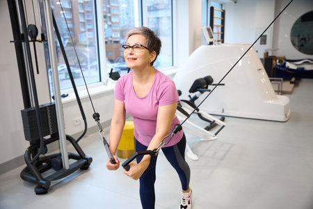 Middle aged caucasian woman doing sport exercise for chest muscles in gym