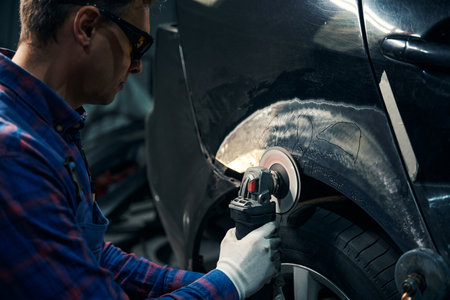 Skilled male working with front fender in tire fittingの写真素材