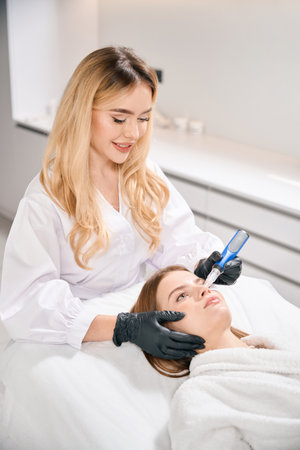 Smiling beautician doing ultrasonic cleaning of woman face skin with skinpen