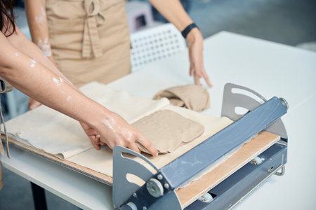 Female working potter rolling out clay slabs in her pottery studioの写真素材