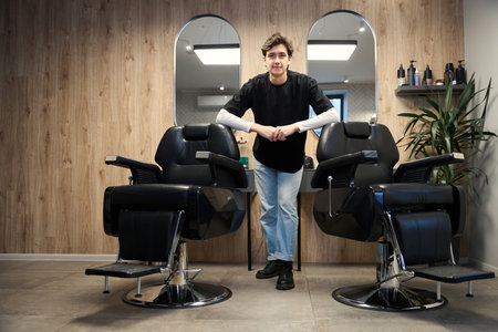Caucasian barber posing at camera in hairdressing salon