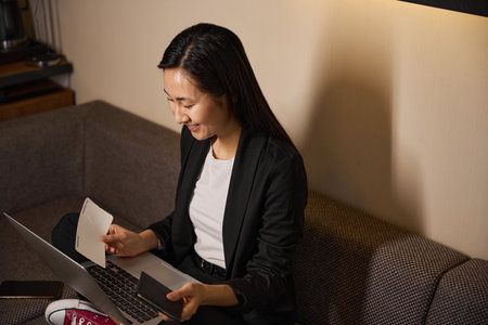 Smiling pretty woman sitting on couch with laptop