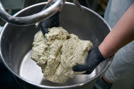 Kitchen worker takes out dough from a dough kneading machine