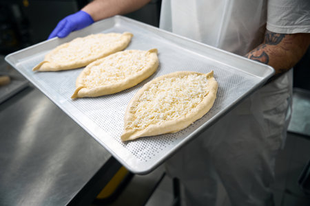 Man in a uniform holds a metal sheet with khachapuriの写真素材