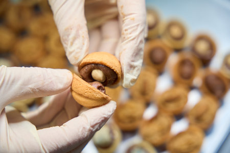 Close-up confectioner pressing together two halves of sweet pastry nutsの写真素材