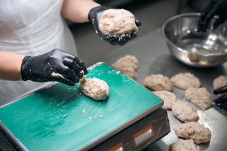 Kitchen worker weighs portioned minced meat for cutletsの写真素材