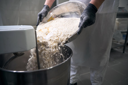 Worker pours flour into a dough kneading machine