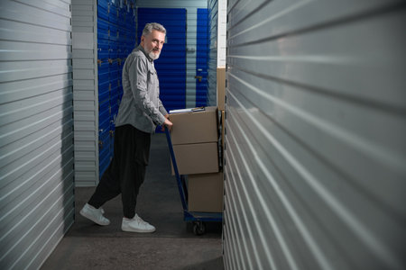 Male carrying large trolley filled with stacked boxes