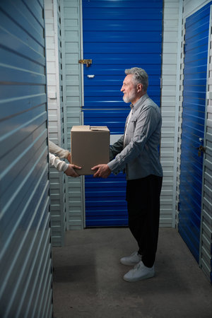 Adult man hands over box in warehouse