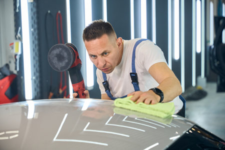 Guy polishes the car body with a special device