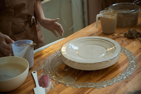 Close up of female ceramist creating ceramic plate from clay in workshopの写真素材
