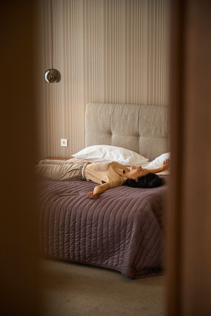 Woman in comfortable casual clothes is lying on a bedの写真素材