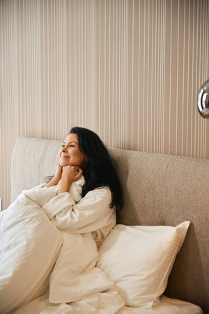Happy woman enjoying morning in cozy bedの写真素材