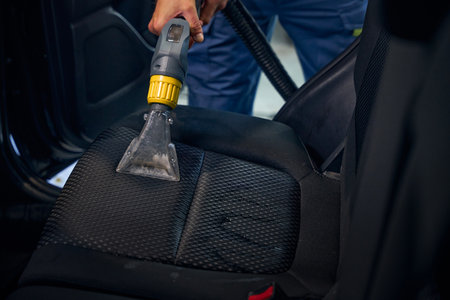 Detailing specialist cleans the interior of car with vacuum cleanerの写真素材